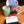 Three ceramic mugs with blue, green, and red stripes are stacked on a wooden surface next to a set of black felt dog coasters with a red ribbon and a card that reads 'love is felt' 
