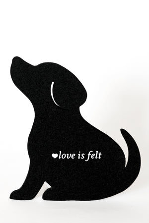 A black felt dog silhouette is a coaster with the white text 'love is felt' and a small heart on its chest, set against a plain white background.